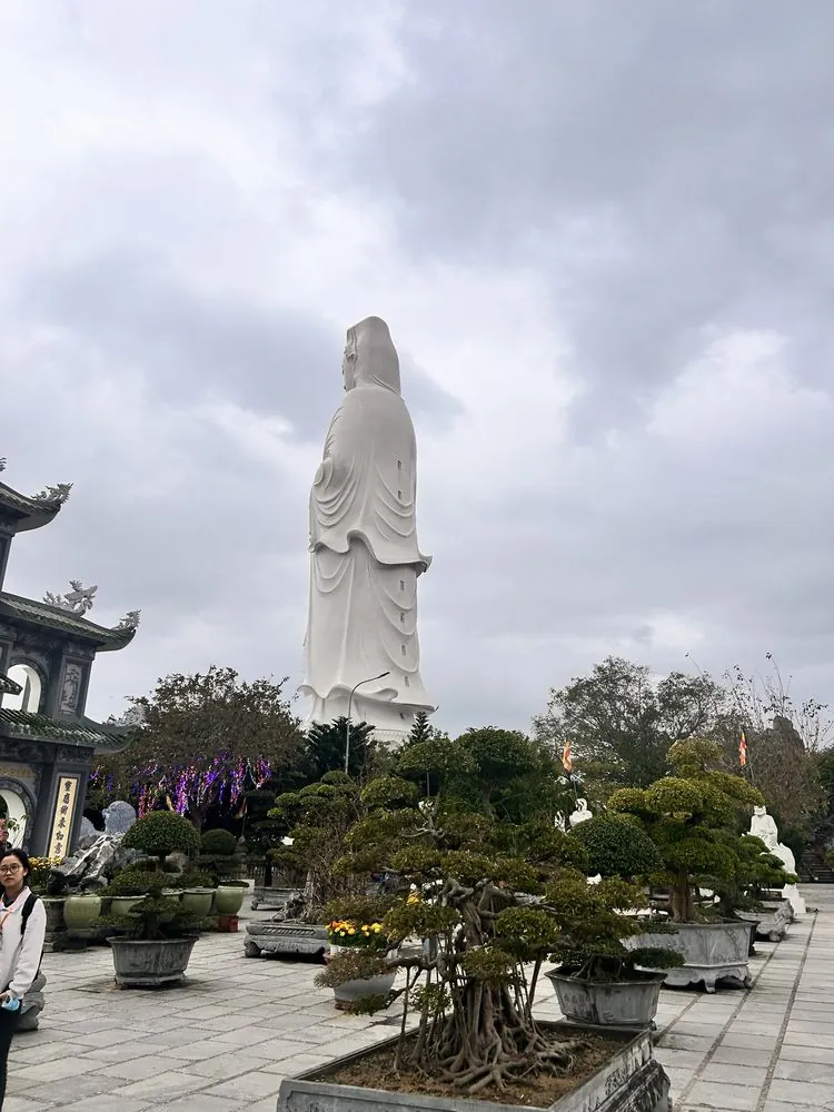レディブッダを背後から、盆栽庭園越しに